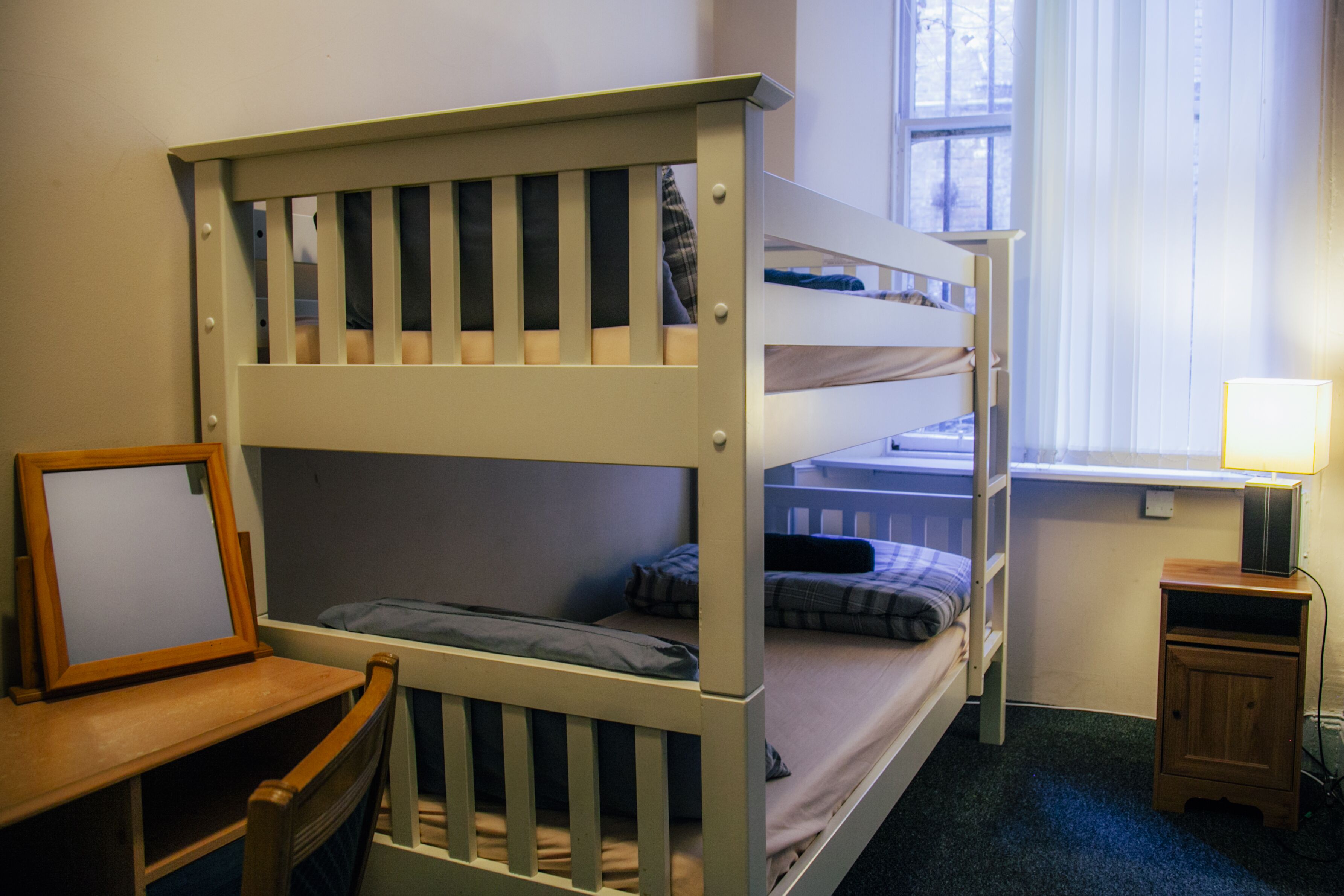 Ein Schlafzimmer mit Etagenbetten, einem Schreibtisch und einem kleinen Schrank.