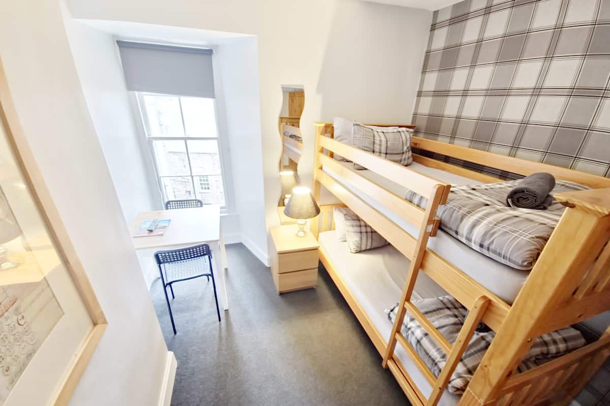 Ein kleines Zimmer mit einem Etagenbett, einem Schreibtisch und einem Stuhl.