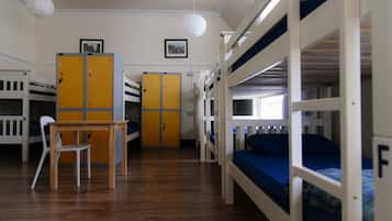Une chambre de dortoir avec des lits superposés, un bureau en bois, une chaise et des casiers.