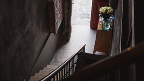 En trappe med gelænder i træ fører op til en platform med en blomstervase.