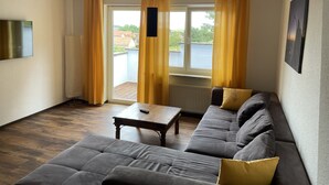 A living room with a grey sofa, a wooden coffee table, and yellow curtains.