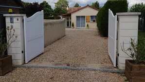 A gated driveway leading to a house with a gravel path.