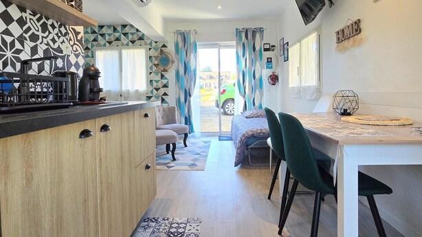 A compact living space with a kitchenette, a dining area, and a bed.