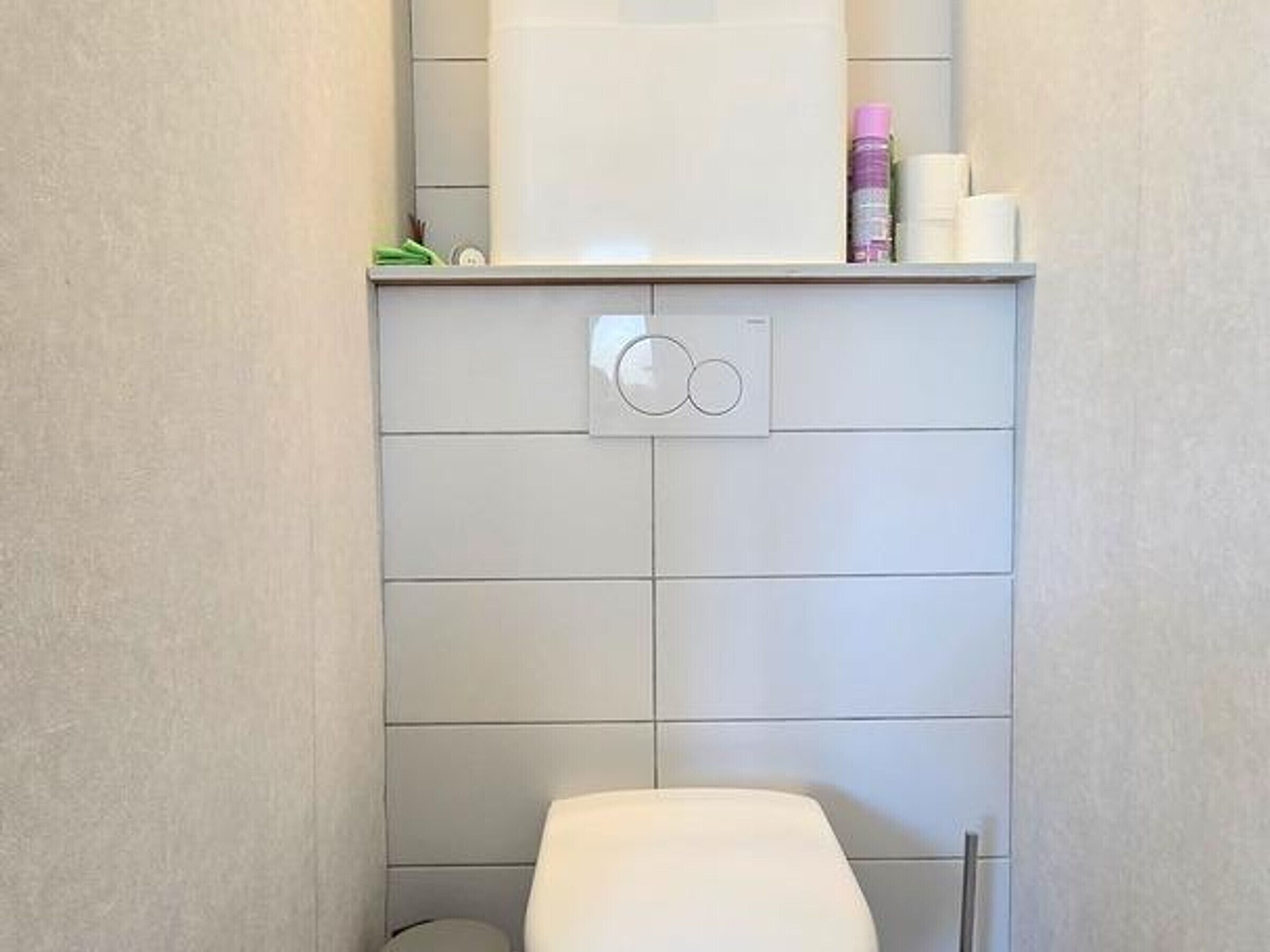 Een badkamer met een toilet, een handdoekhouder en een zeepdispenser aan de muur.