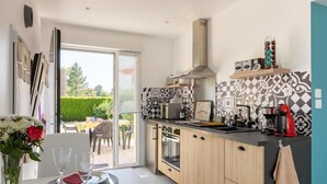 A compact kitchen with a dining area, a sliding glass door leading to a patio, and a patterned backsplash.