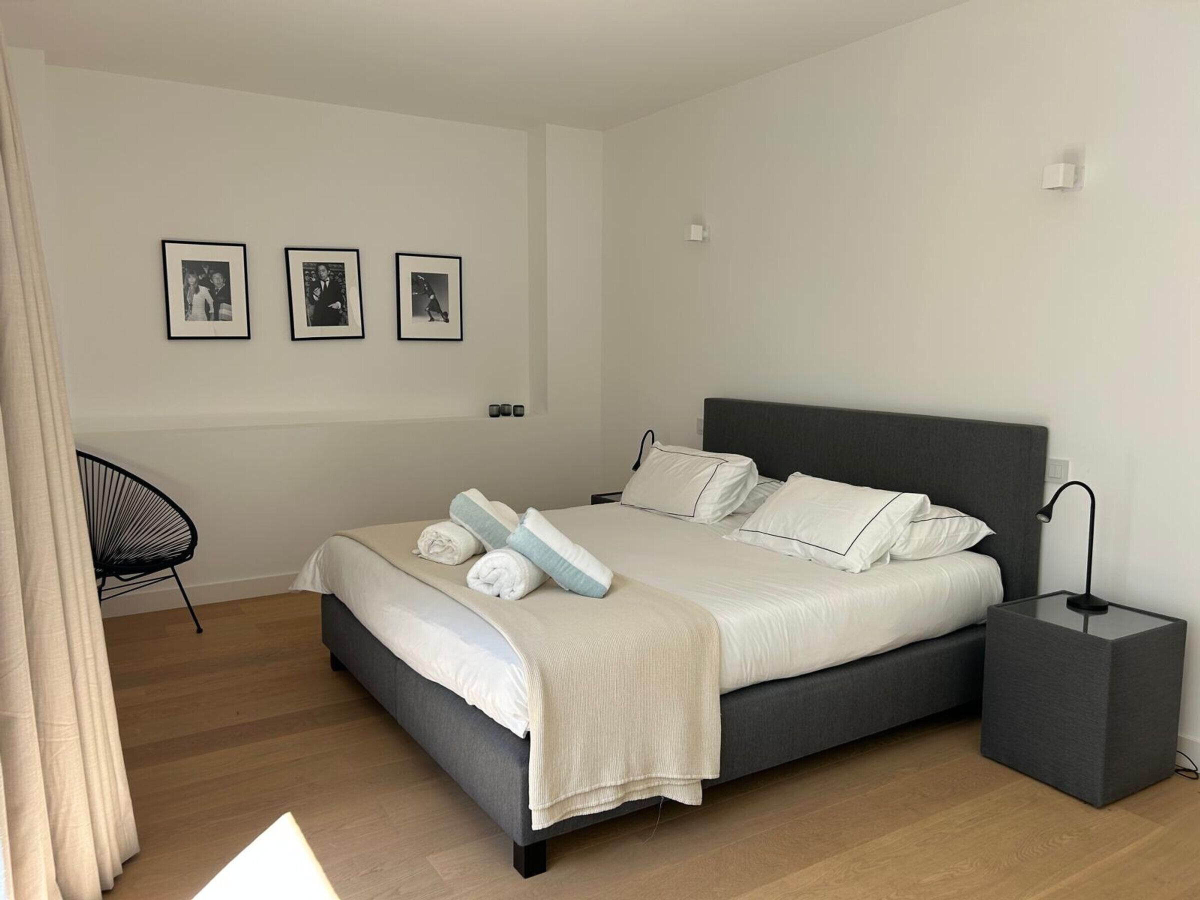 Un dormitorio moderno con una cama grande, mesitas de noche y una silla.