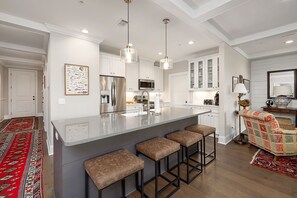 Una cocina moderna con una isla central, taburetes de bar, microondas y refrigerador.