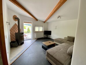 Un salon avec un canapé, une table basse, un téléviseur et une cheminée.