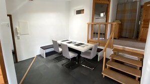 Un interior moderno con una mesa de comedor, sillas, una escalera y una lámpara de techo.