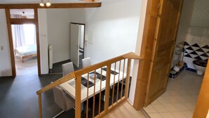 Un interior de varios niveles con una escalera, un comedor y un baño con baldosas estampadas.