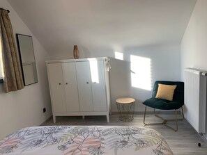 A bedroom with a bed, a wardrobe, a chair, and a radiator.