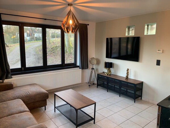A living room with a sofa, a coffee table, a TV, and a window with curtains.