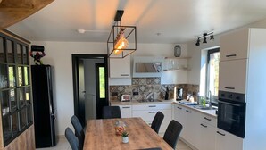Una cocina moderna con una mesa de comedor de madera, sillas negras, horno empotrado y microondas.