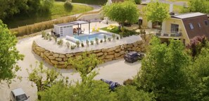 A residential property with a swimming pool, stone wall, and a covered patio area.