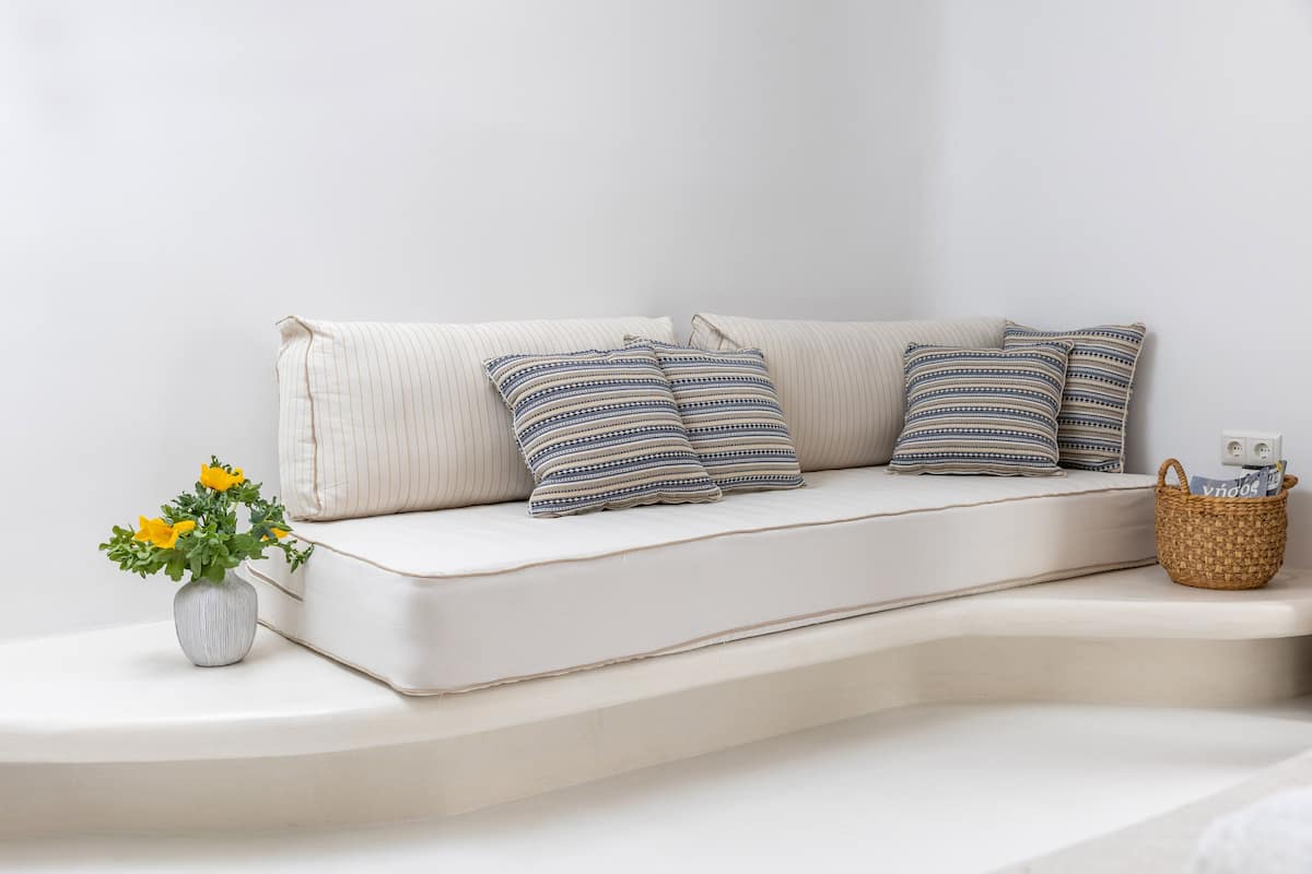 A modern sofa with striped pillows and a woven basket on a white platform.