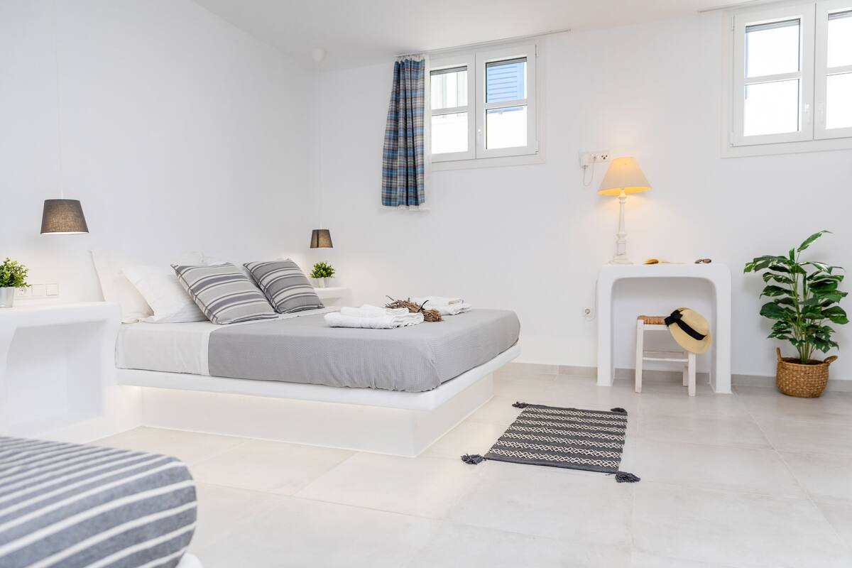 A modern bedroom with a bed, bedside tables, a lamp, a plant, and a fireplace.