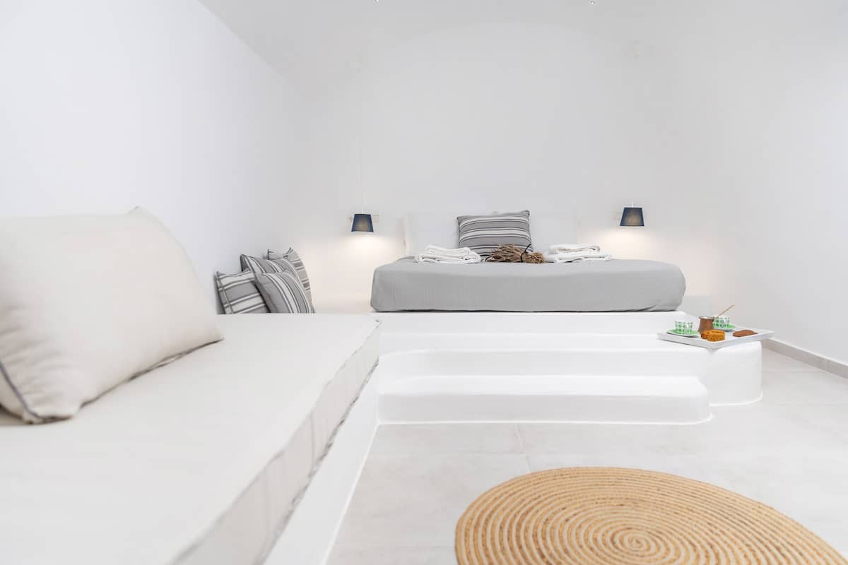 A minimalist bedroom with a bed, two bedside tables, and a sofa.
