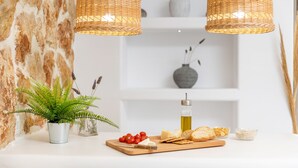 A kitchen counter with a cutting board, cheese, tomatoes, bread, and a bottle of oil. - Krina Mare (Naxos)