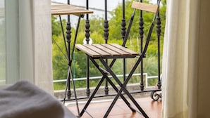 A balcony with a wooden table and chair, overlooking a river and greenery. - Hotel Ría de Suances (Suances)