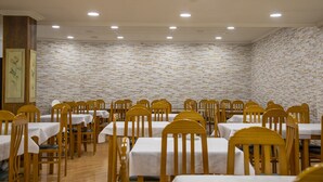A dining area with multiple tables and chairs, a patterned wall, and recessed ceiling lights. - Hotel Ría de Suances (Suances)