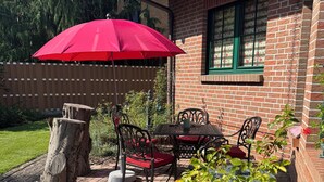 A patio with a brick table and chairs, a red umbrella, and potted plants. - Beautiful, exclusive, large apartment for nature lovers, forest and lake region (Storkow (Mark))