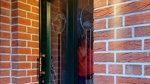 A green door with a glass panel, a brass doorbell, and a brick wall with a textured pattern. - Beautiful, exclusive, large apartment for nature lovers, forest and lake region (Storkow (Mark))