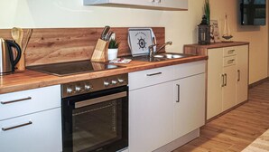 Una cocina moderna con encimera de madera, electrodomésticos de acero inoxidable y armarios blancos.