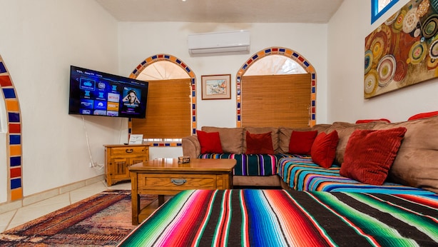 Ein Wohnzimmer mit einer Couch, einem an der Wand montierten Fernseher und einem gemusterten Teppich.