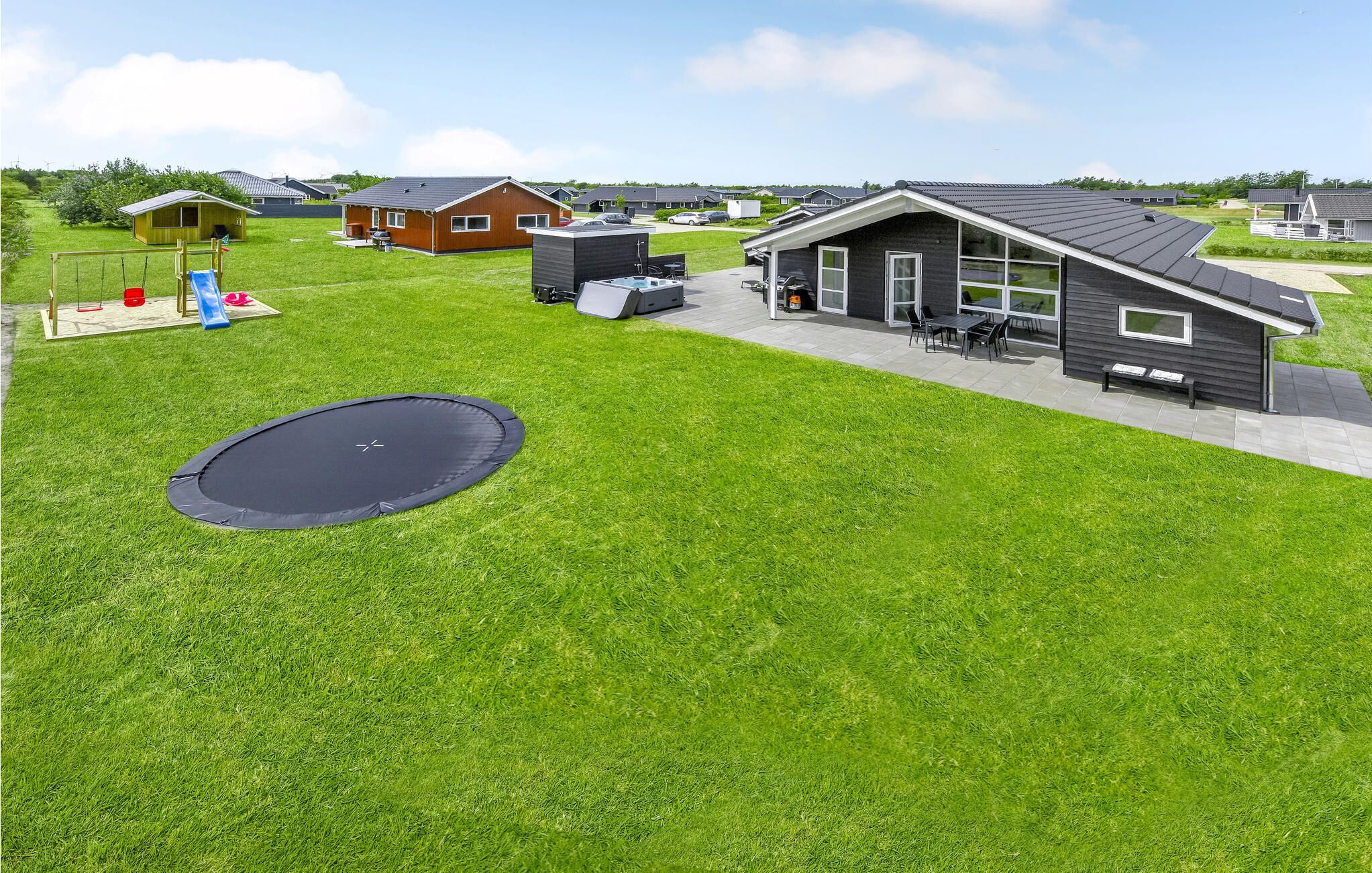A residential area with houses, a trampoline, and a patio with outdoor furniture.