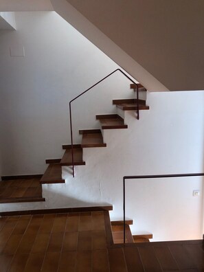 A staircase with wooden steps and a metal handrail, leading to a higher floor.