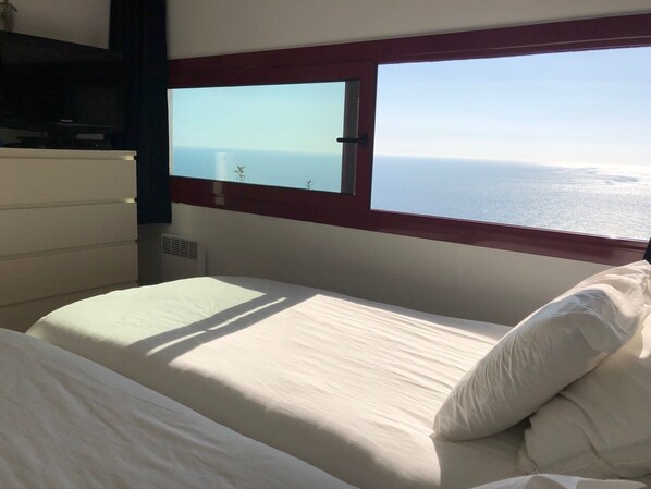A bedroom with a bed, a dresser, and a window with a view of the sea. - Air-conditioned house with a private garden overlooking the sea (Palafrugell)