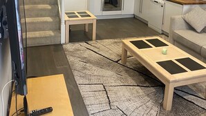 Una cocina moderna con armarios blancos, horno integrado y microondas. En la sala de estar, hay una mesa de centro de madera y un sofá.