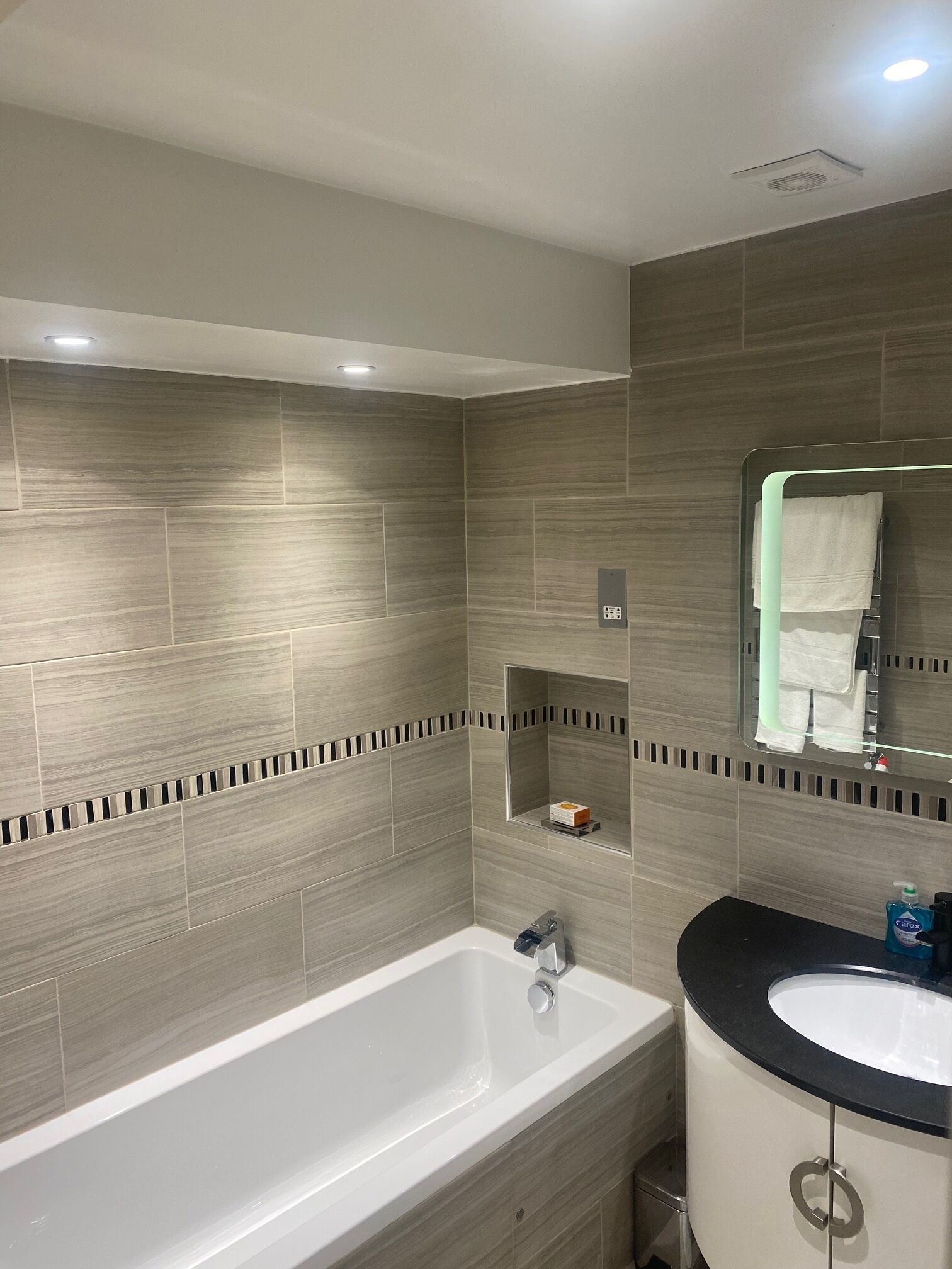 Une salle de bain moderne avec une grande baignoire, un lavabo et un miroir.