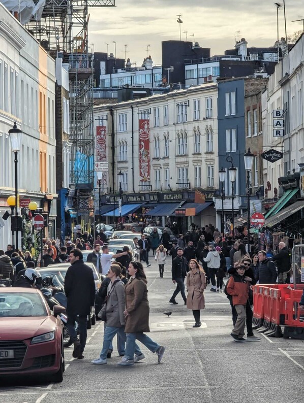 A busy urban street with pedestrians and parked cars.