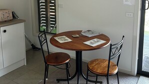 Ein kleiner Essbereich mit einem runden Holztisch, zwei Stühlen und einem gerahmten Bild an der Wand.