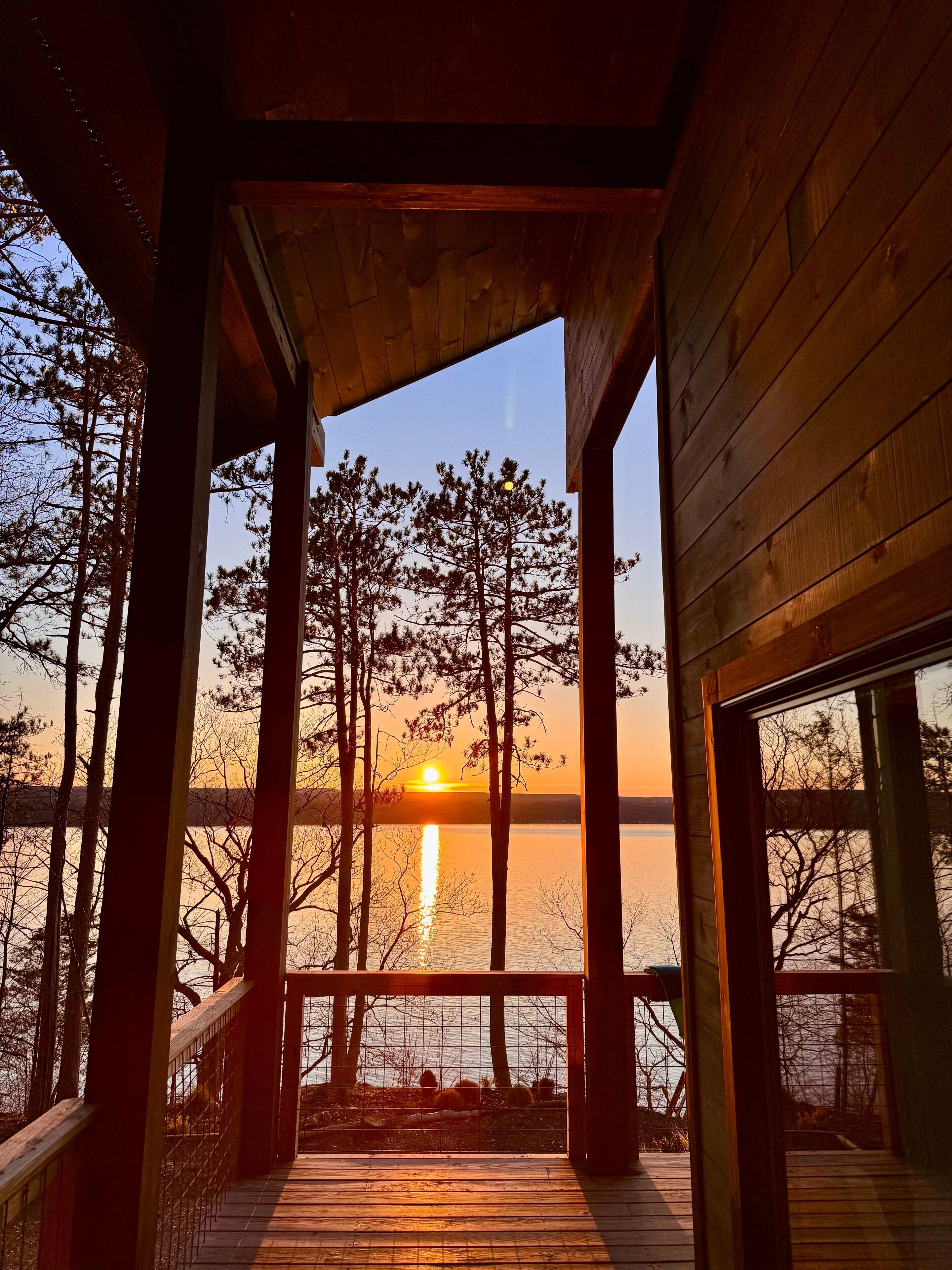 A wooden deck with a railing overlooking a body of water and trees.