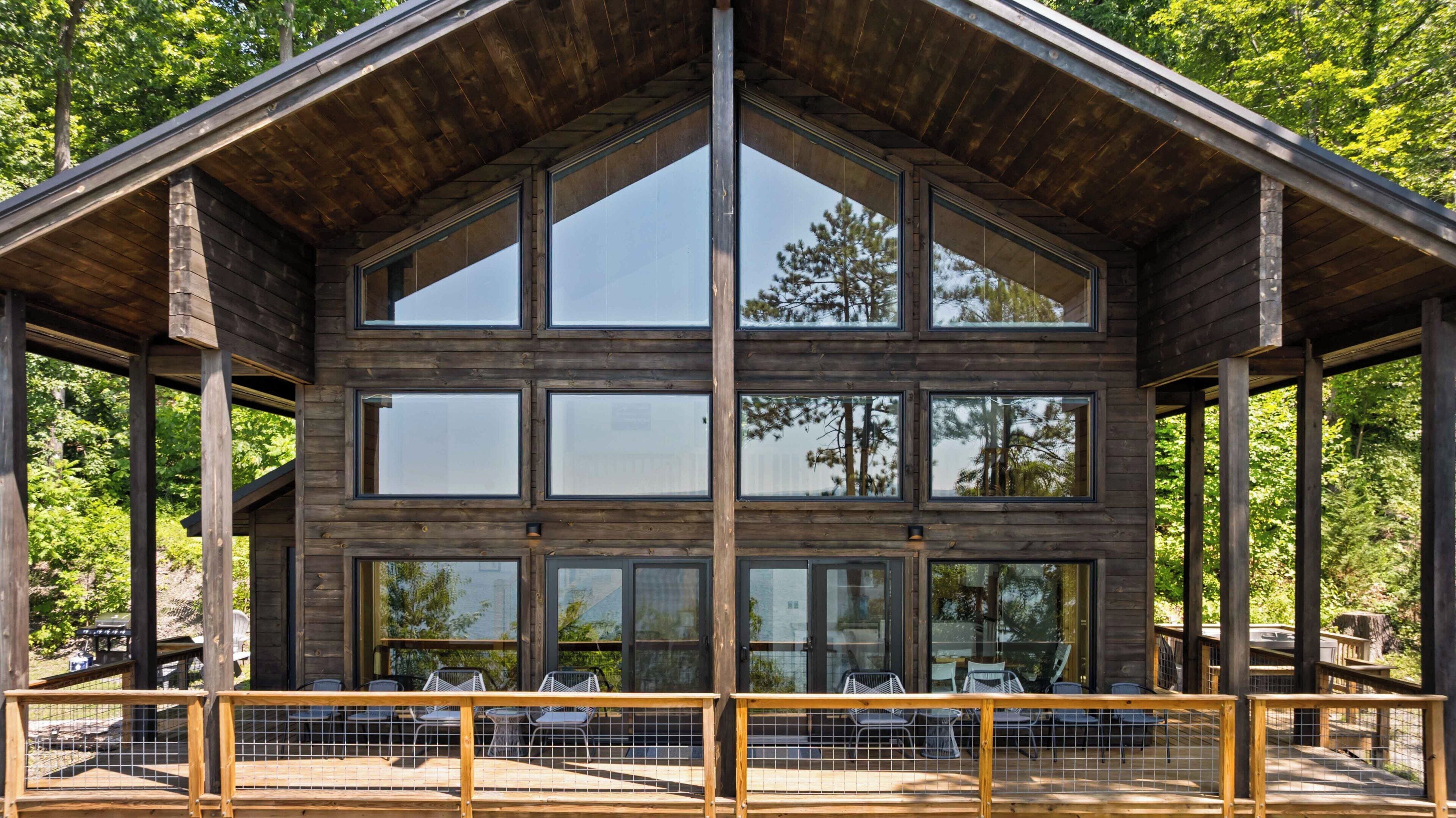 A large wooden cabin with multiple windows and a covered deck area.