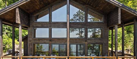 A large wooden cabin with multiple windows and a covered deck area.