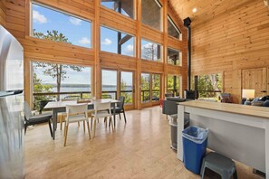 Una cocina amplia con ventanas grandes, un comedor con sillas y vistas al exterior.