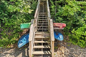 Een houten ladder met aan weerszijden kajaks, omgeven door groen.