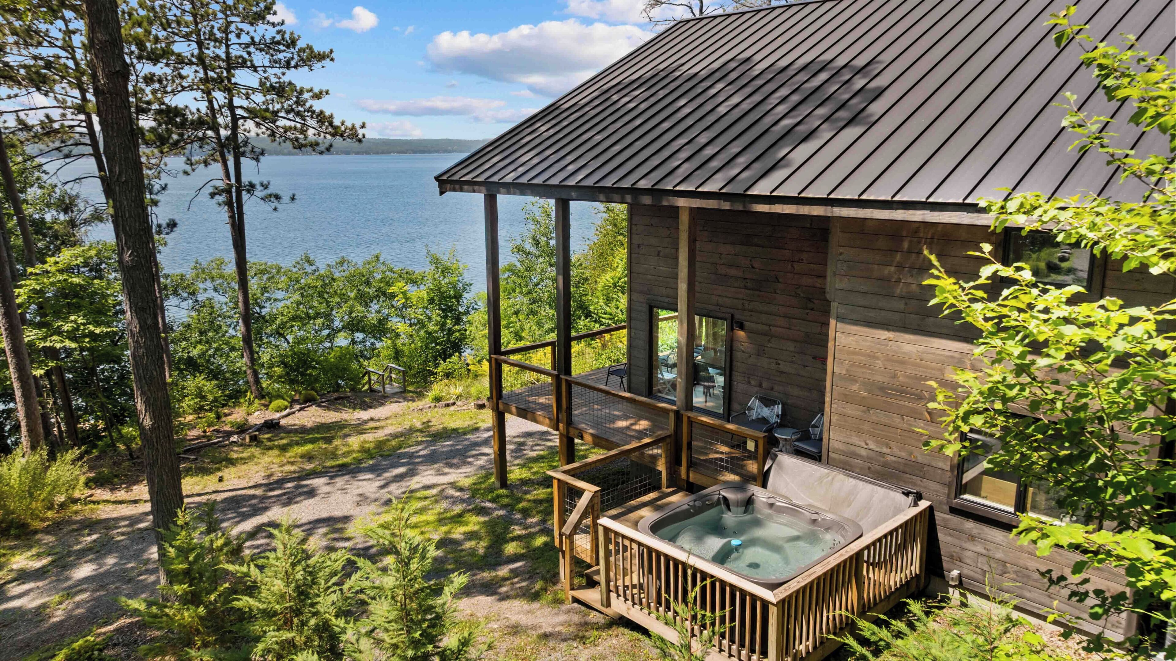 Une cabane avec un bain à remous, une terrasse en bois et une vue sur un lac.