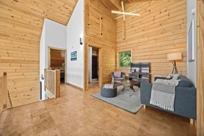 A spacious living area with a high ceiling, wooden walls, a sofa, a television, and a staircase. - Hygge on Seneca: "Relaxing Seneca Lake Getaway!" (Lodi)