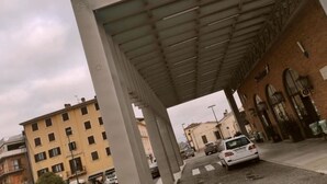 Un paso elevado cubierto para peatones, con un edificio a un lado y una calle al otro.