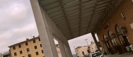 A covered pedestrian walkway with a building on one side and a street on the other.