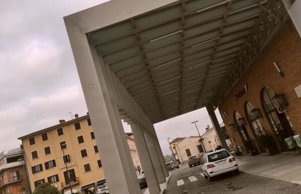 A covered pedestrian walkway with a building on one side and a street on the other. - Hotel Centrale (Chiusi)