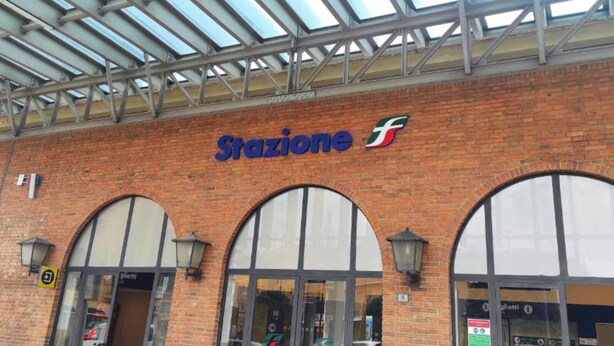 Un edificio de ladrillo con un gran letrero que dice “Stazione” y un logotipo encima.