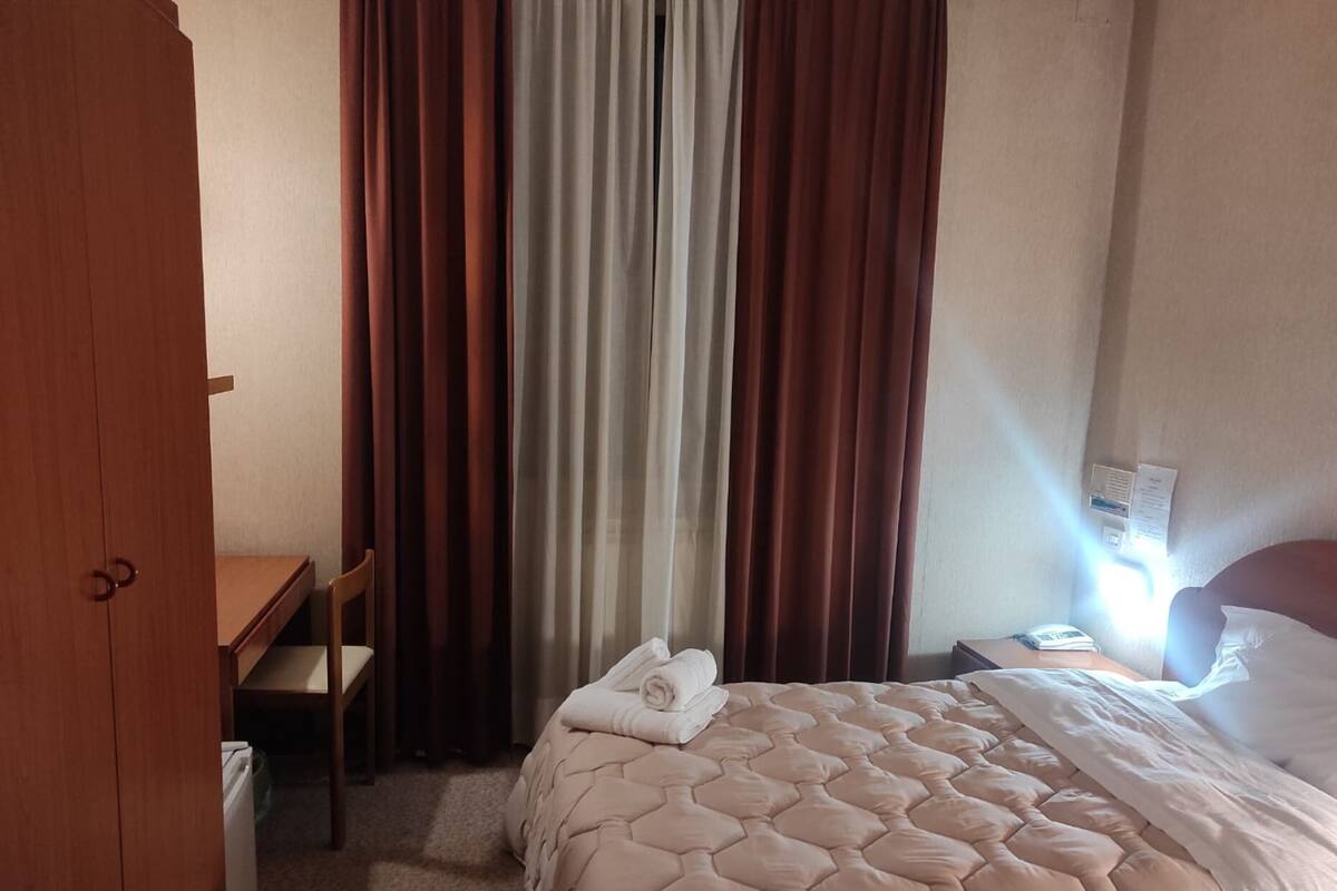 A hotel room with a bed, a desk, and a chair.