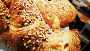 Una exhibición de diversos pasteles, incluyendo croissants y panecillos, en una panadería.