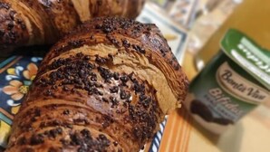 Un croissant con chispas de chocolate sobre un plato.