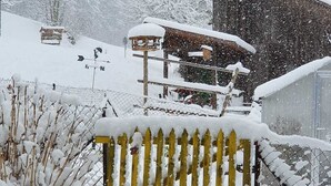 Une clôture en bois recouverte de neige, avec une structure couverte également recouverte de neige en arrière-plan.